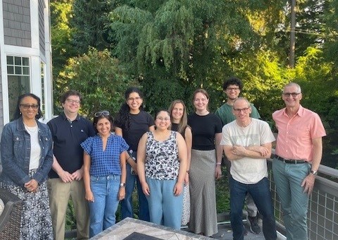 Group photo taken outside on a deck with trees in the background.